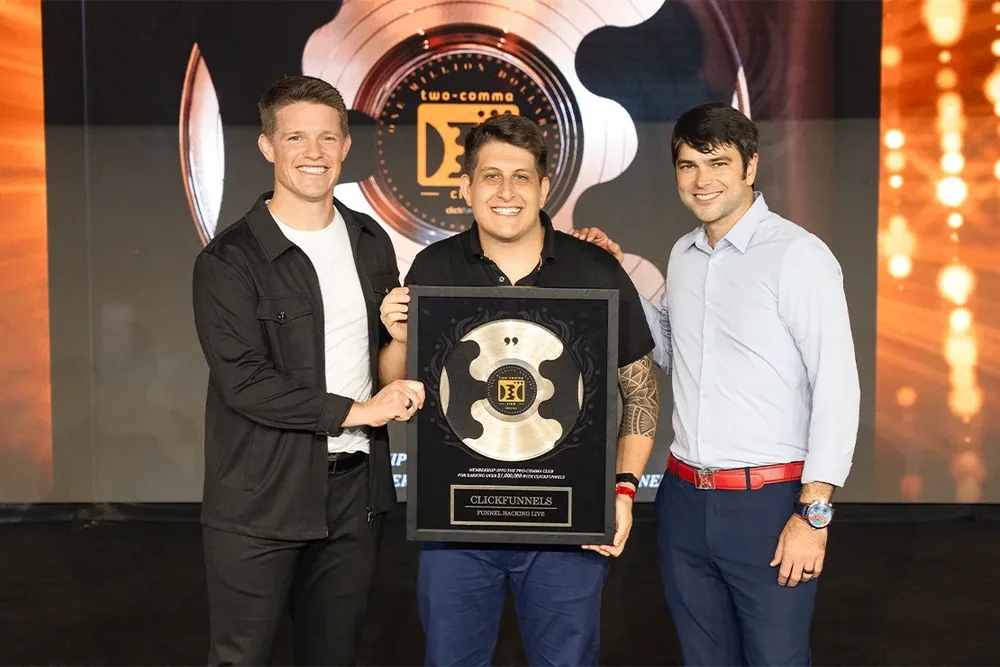 Lucas Neves no palco, no centro da foto, segurando a placa do Two Comma Club